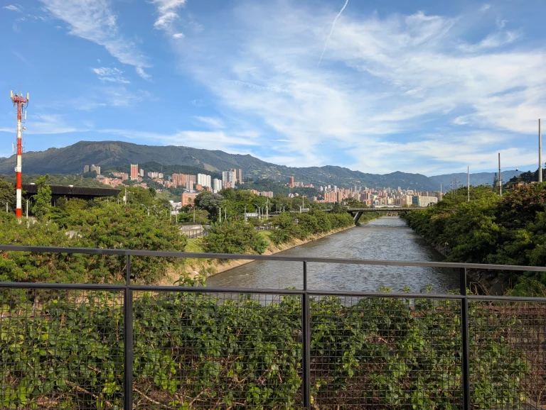 Der urbane Stadtpark Parques del Río in Medellín – eine grüne Oase inmitten von modernen Gebäuden und Bergen im Hintergrund.